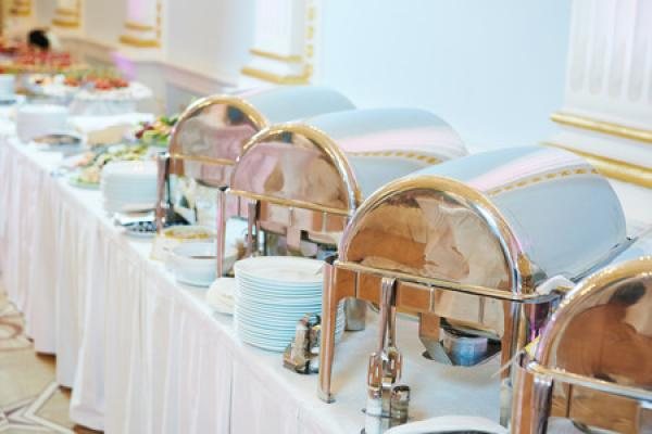 A Kama'aina Catering buffet line of silver chafers on white linen