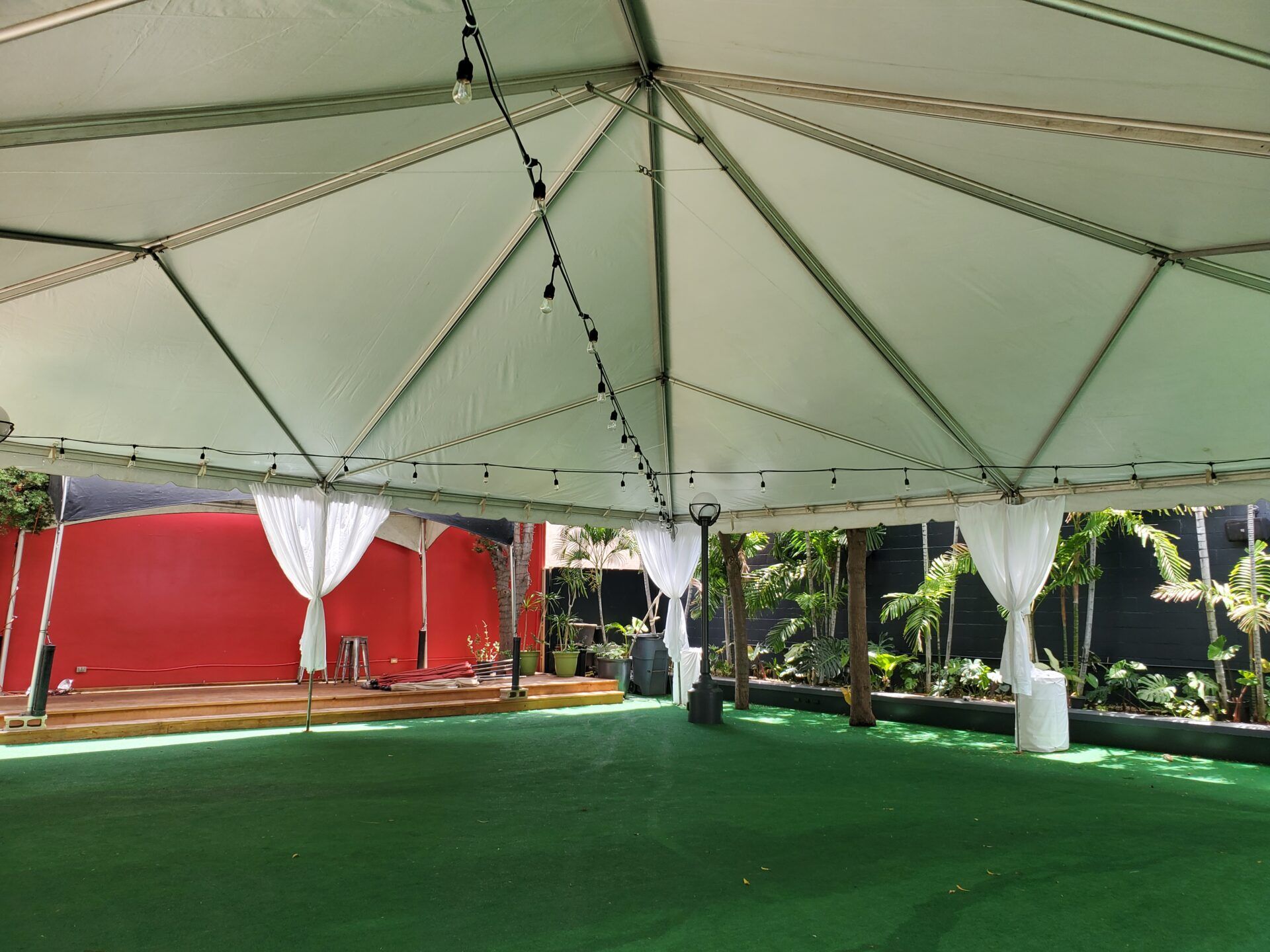 A Kama'aina white frame tent set up on a lawn, sides open, ready for an event