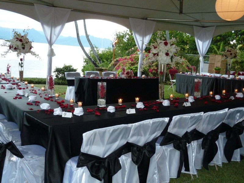 A Kama'aina Catering reception at Kualoa Ranch's Molili Gardens: long tables in black and white linens under a white tent