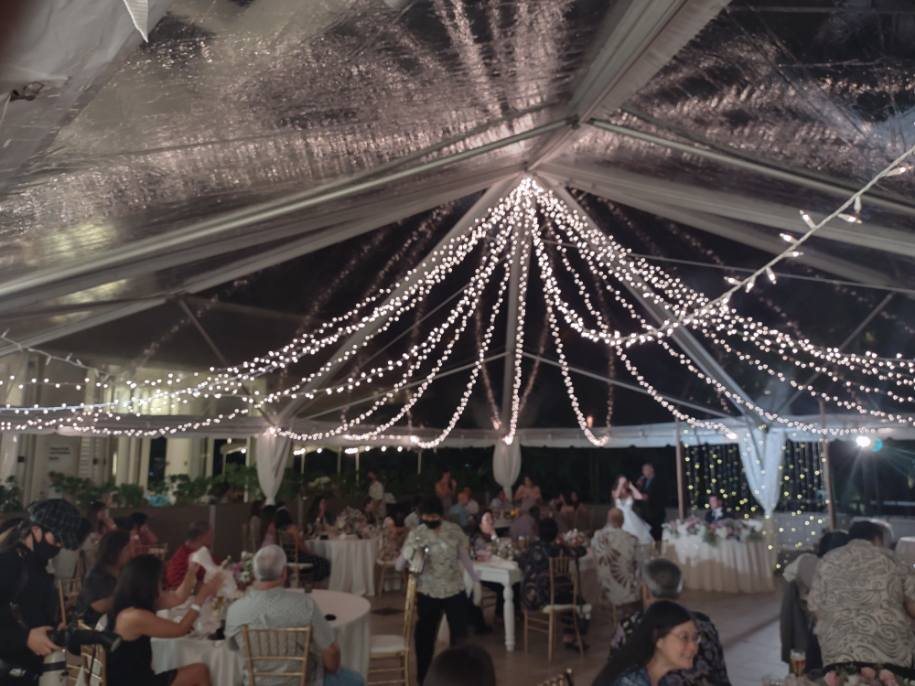 A clear-top tent reception at night, string lights over the tables